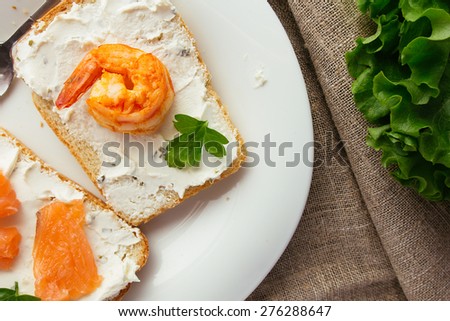 Wheat bread toasts with cream cheese, smoked salmon and shrimp selective focus horizontal