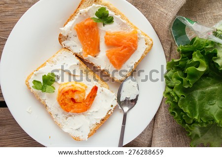 Wheat bread toasts with cream cheese, smoked salmon and shrimp selective focus top view