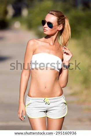 Attractive fit woman in sportswear training outdoors, female athlete with perfect body.