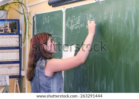 MOSCOW OCTOBER 3 - Unidentified student writes in chalk on green school board problem solving in mathematics. Teachers' Day in Moscow school October 3, 2014