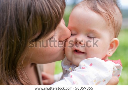 Mom kisses her little daughter, played in the park
