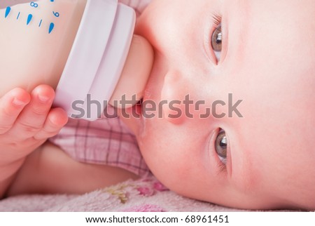 The small child drinks milk from a small bottle