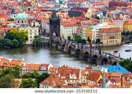 Tourism and sightseeing, view from above over famous sight of Prague Charles Bridge and Old Town Eastern tower. Good weather, summer day, river Vltava, red tiled roofs, crowd of tourists on the bridge