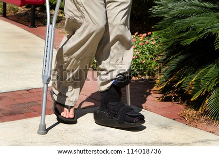 Man uses crutches along with a foot and ankle brace to help him walk after an accidental injury.