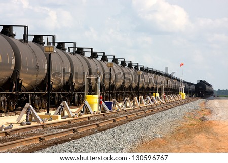 Long lines of railroad oil tanker cars stretch off into the distance down the train tracks waiting to be unloaded.