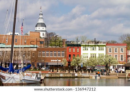 Annapolis, Maryland, Usa - April 12, 2013: Tourists Shop Along The Waterfront In Historic Downtown Annapolis, Maryland, Usa, The State Capital, Dome Visible In The Background, On April 12, 2013.