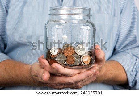 Man holds a glass jar containing United States coins and money.