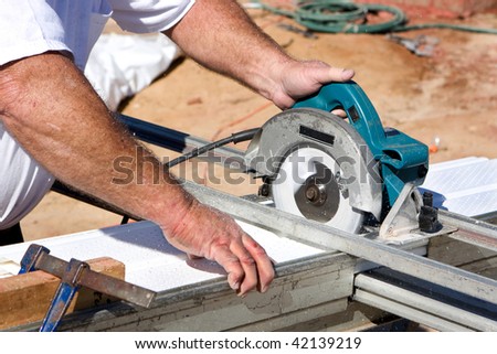 Construction worker uses a electric powered circular saw to cut soffit for a home being built.