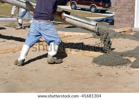 Construction worker directs a chute to pour concrete for a driveway at a new home site.