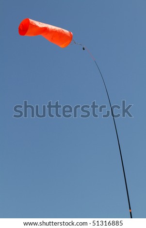 Bright orange wind sock against a blue sky indicates the direction of the wind.