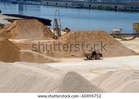 Front end loader moves gravel at a gravel and materials storage operation plant by a river.