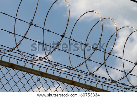 Razor wire and barbed wire top a fence to prevent people from climbing over.