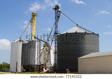 Grain storage elevators and silos for storing harvested crops against a blue sky.
