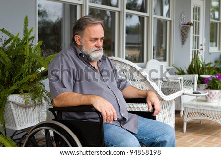 Depressed paraplegic man sits in his wheelchair on the patio.