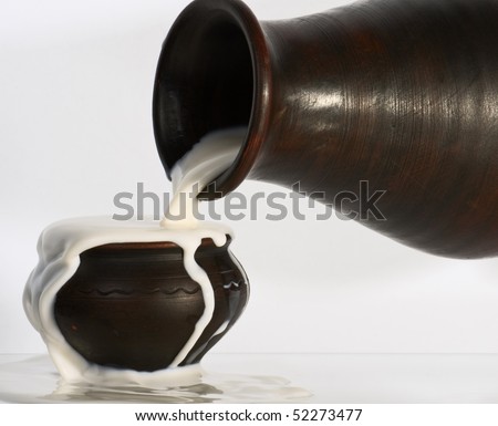 Milk pouring from a jug over the edge of the cup.