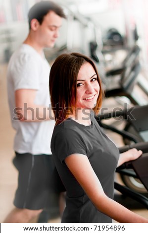Beautiful girl running on a treadmill in sport club