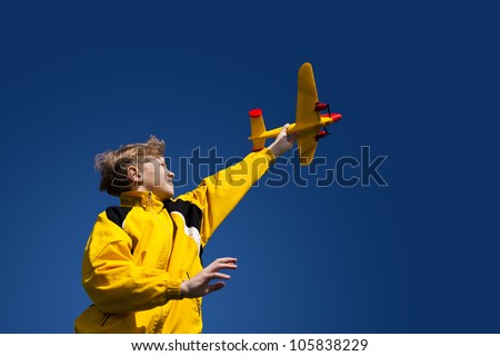 The boy holds in a hand plane model against the sky