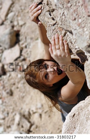 The girl hangs on the brink of a rock and asks about the help