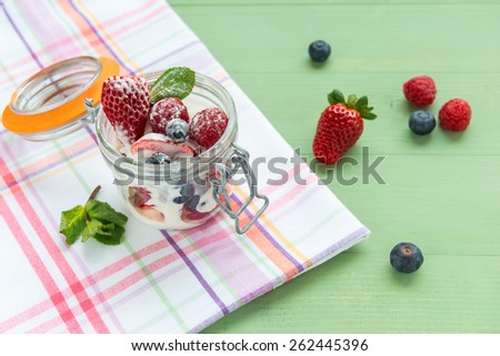 Wild berries with yogurt in a glass jar. View from above