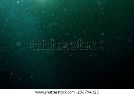 Abstract blue background with floating and reflecting dust