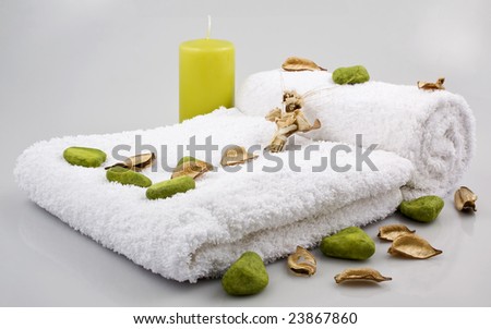 Bathroom arrangement with white towels, green candle, decorative stones and dry flowers
