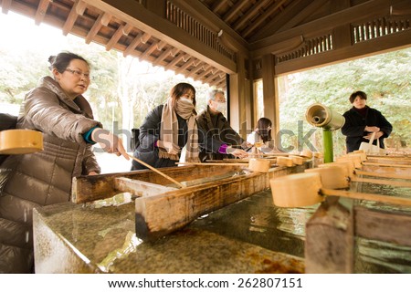 TOKYO, JAPAN - FEBRUARY 4, 2015: Unidentified people rinse hands and mouth at Temizuya before entering the main shrine at Meiji Jingu Shrine located in Shibuya.