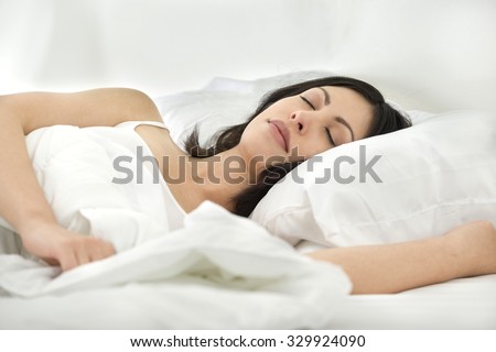 Calm Caucasian young woman with medium black hair in athletic costume sleeping