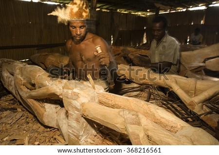 West Papua, Indonesia, Circa May 2011. Asmat tribal men carving totem poles in Omandeseb Village.
