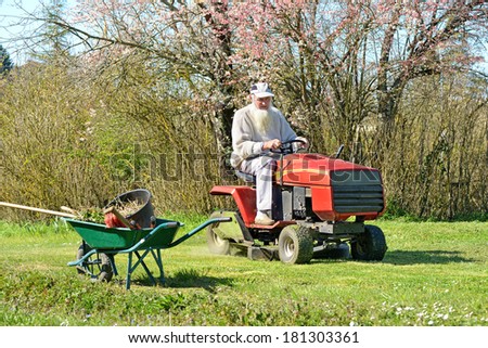 an senior who cutting the grass with lawn mower tractor