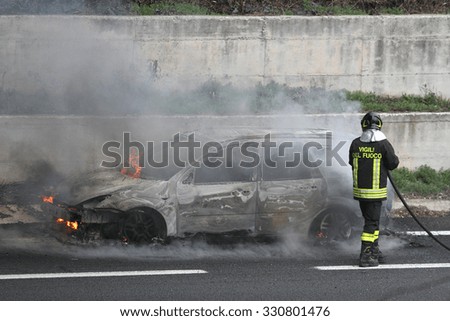 Burning car with firefighters, jackets say firefighters