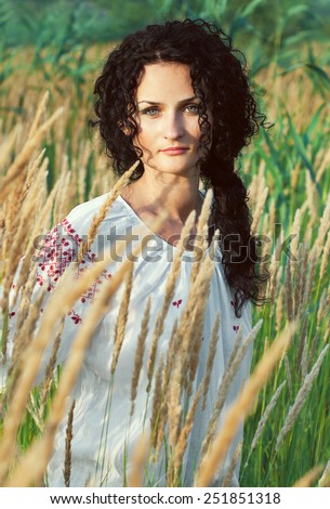 Â Portrait of young brunette in ukrainian traditional blouse (shirt) walking through fields. Outdoor shot