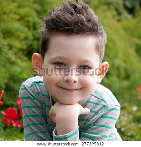 Stylish baby boy with dark hair in  striped polo-neck. Smile. Hipster style. Outdoor shot