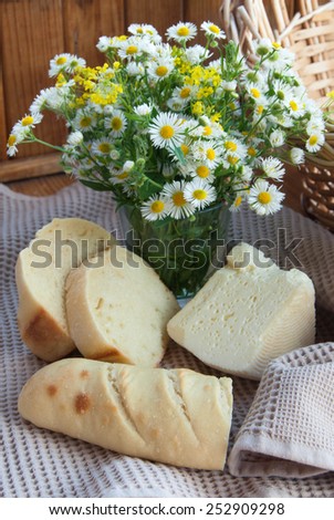 Still life with homemade cheese, bread and flowers