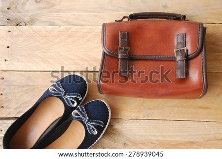 accessories of young women including a blue shoes and brown shoulder bag on wooden background in top view