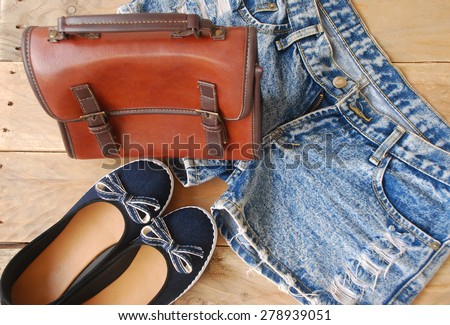 accessories of young women, including a denim shorts, dark blue shoes and brown shoulder bag