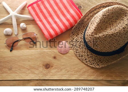 women\'s accessory for go to the beach include sunglasses, red striped towel and hat decorated with shells and starfish on wooden background