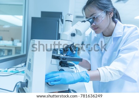 Young asian scientist looking through a microscope in a laboratory.Thailand people doing some research.