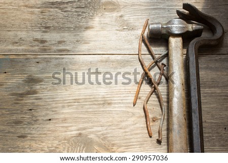 old rusty nails and hammer, nail puller on wooden background, space for text