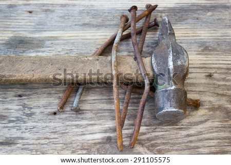 old rusty nails and hammer on wooden background