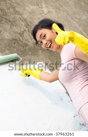 Woman happy doing a good painting job and showing thumb up