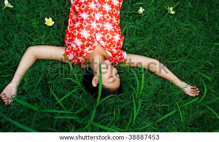 Asian young woman lay down and take a rest on the green grass