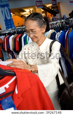 Active asian elderly woman shopping for a gift at a fashion store during sale season