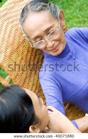 asian elderly mother and her daughter having conversation in the garden