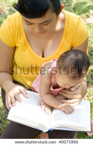 mother read book and babysitting her baby girl