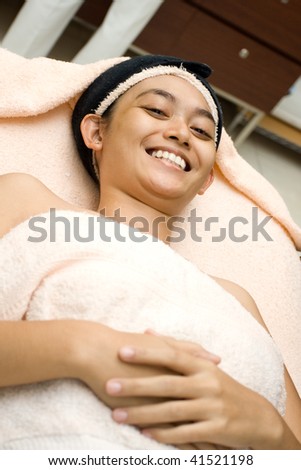portrait of happy asian young woman having facial treatment at beauty clinic