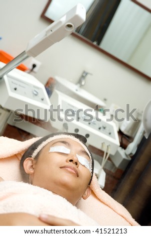 asian young woman having facial treatment using herbal steamer at beauty clinic