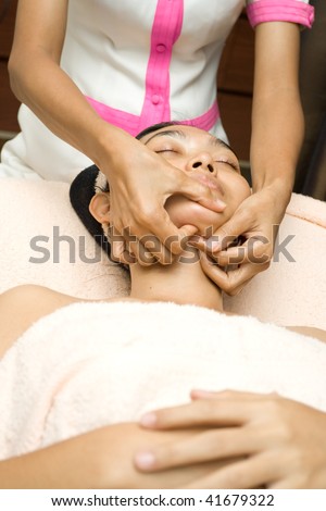 asian young woman having her face massage in facial treatment session at beauty clinic