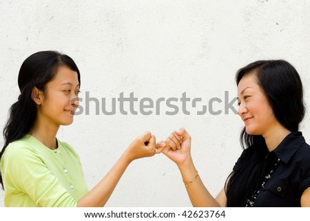 two asian female teenager make peace to each other after the fights. bury the hatchet