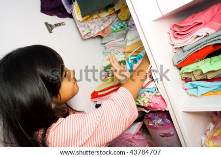 asian little girl arranging her clothes collection in the closet