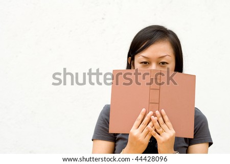 college girl cover her face with a literature on white background